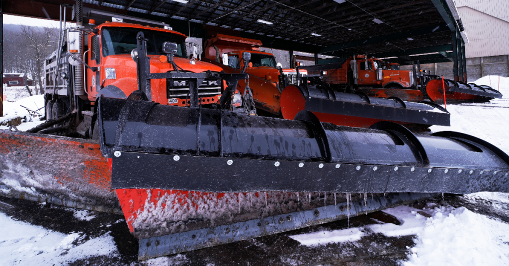 Snow plows lined up under shelter.