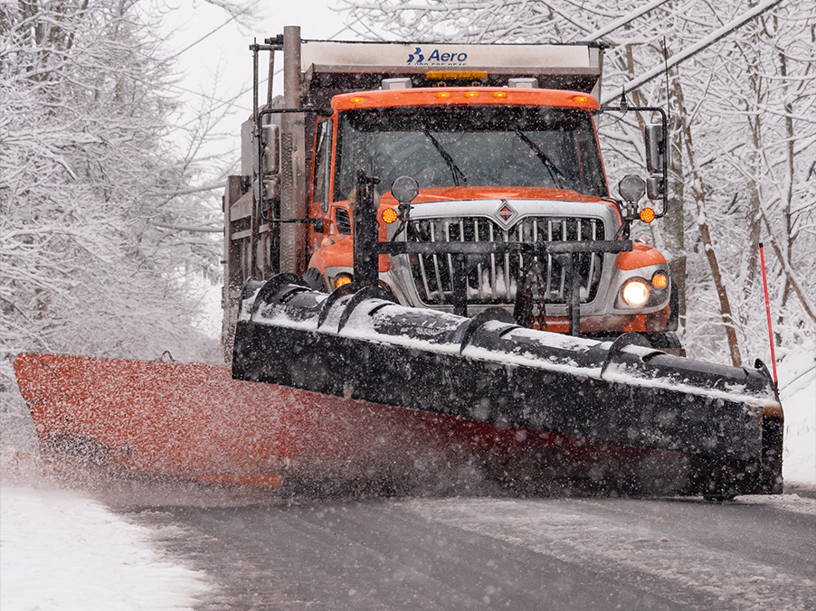 Snowplow plowing road in snowfall.