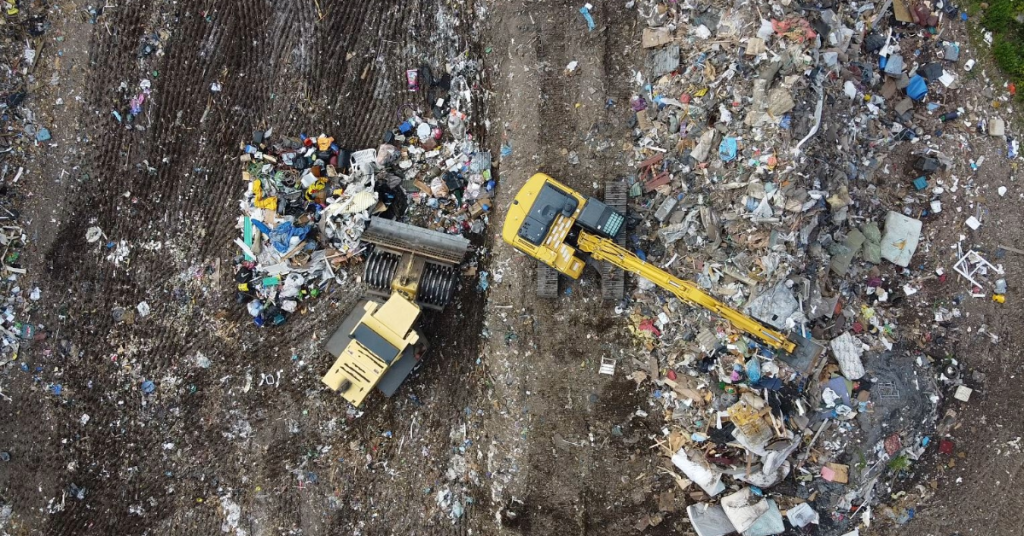 Image is overhead view of heavy machines working on top of landfill.