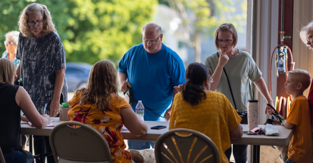 Public health staff sit with backs to camera, while members of the public talk to them during a rabies vaccination clinic.